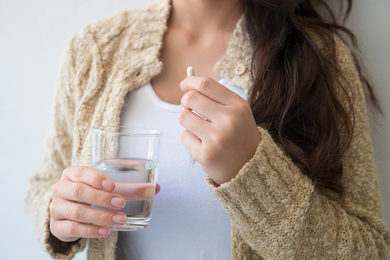 Close up of a woman holding a glass of water in one hand and a tablet in another