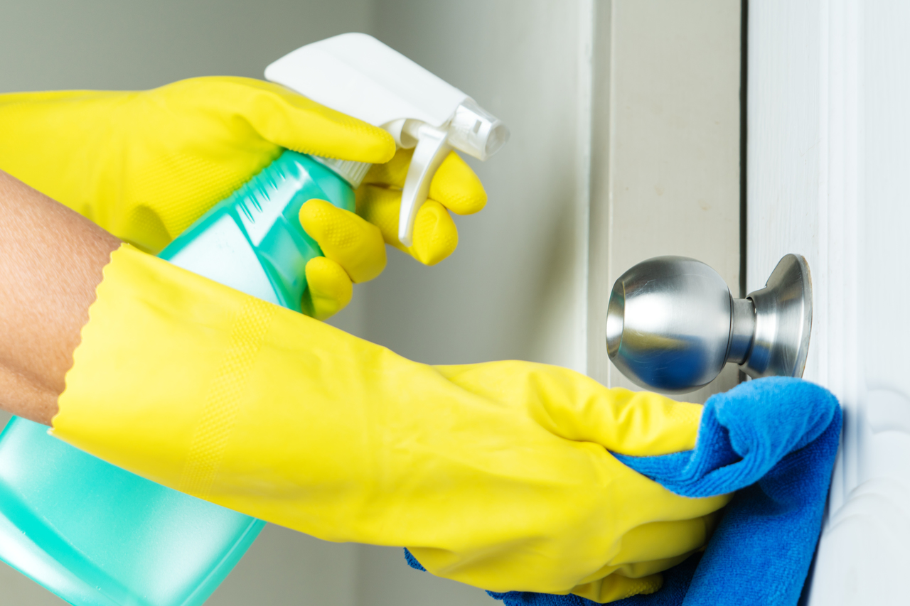 A person disinfecting a doorknob