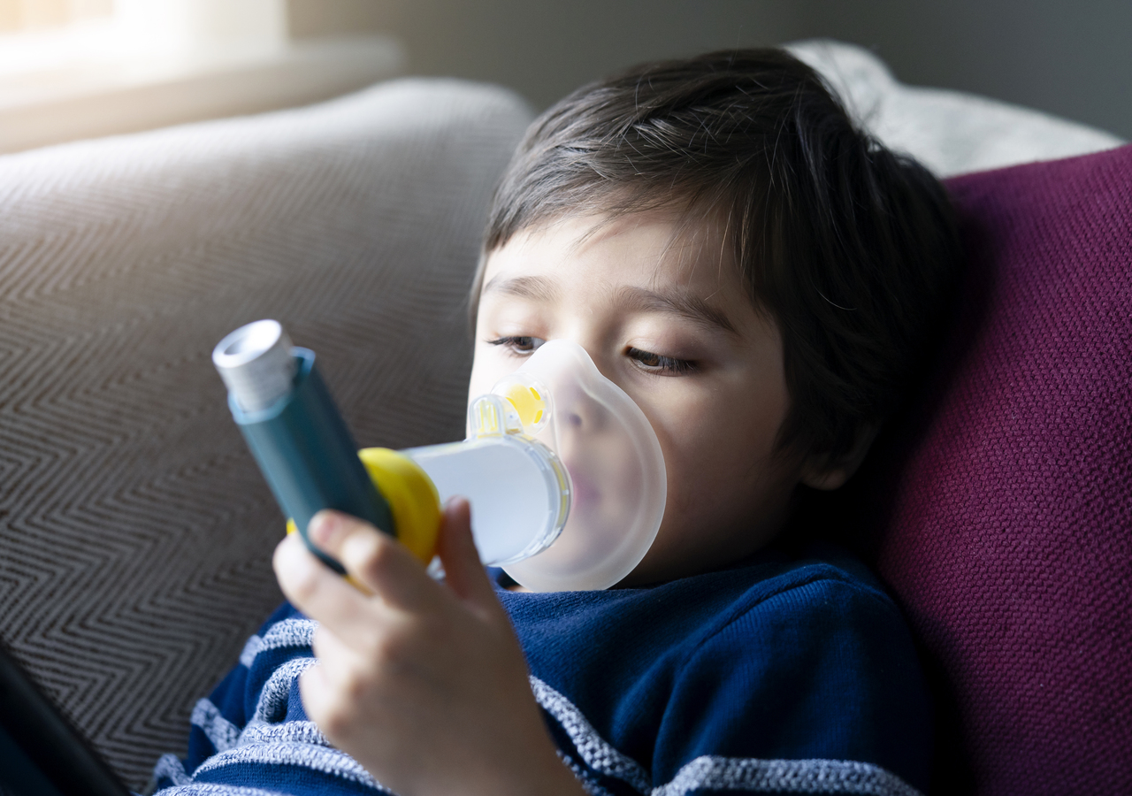 A kid with asthma using an inhaler mask