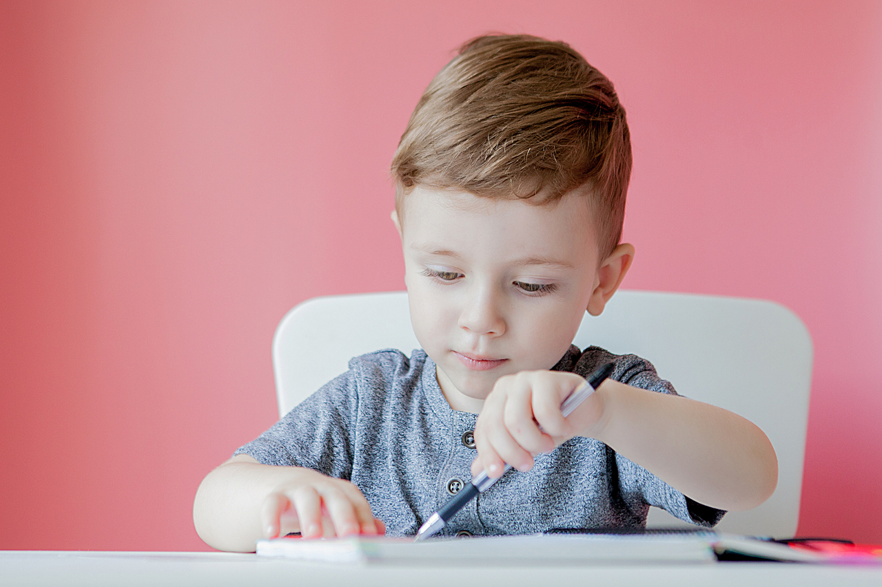 A little boy having trouble holding a pen